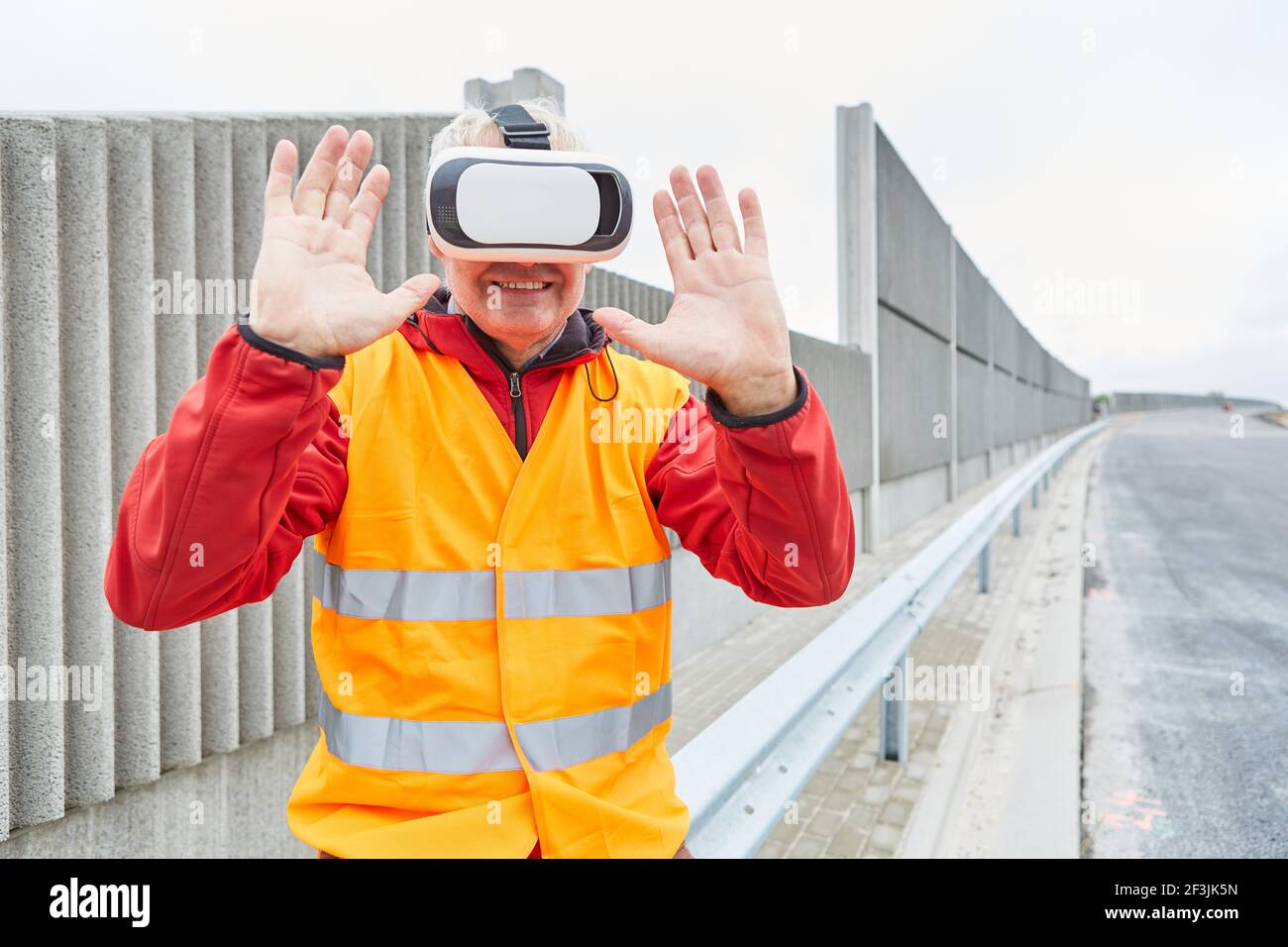 Construction worker uses visualization of the construction site through VR glasses for road construction planning Stock Photo