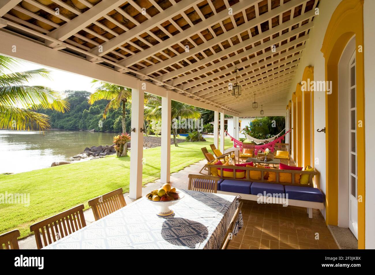Private home in Parati Brazil. Back terrace, overlooking the sea, with wooden table and chairs. Decorated with cushions. Stock Photo