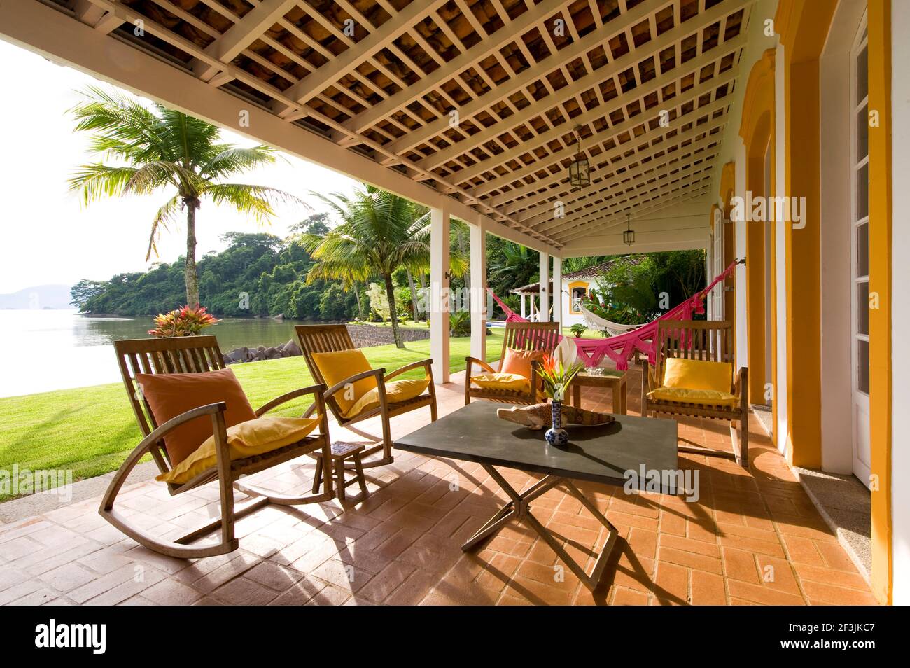 Private home in Parati Brazil. Back terrace, overlooking the sea, with wooden table and chairs. Decorated with cushions. Stock Photo