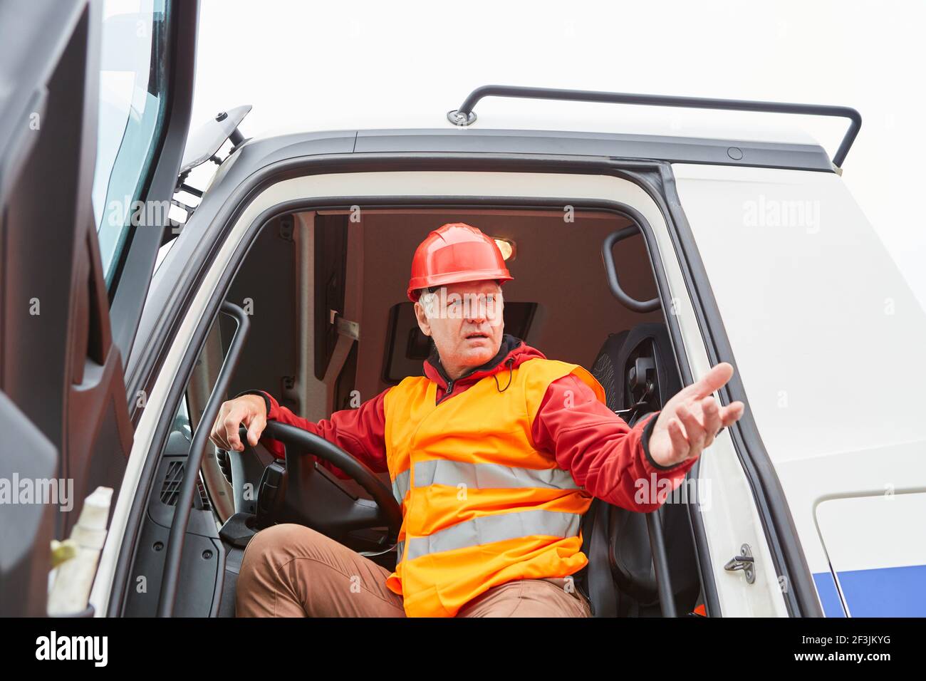 Worker as a truck driver in the cab with a delivery for the