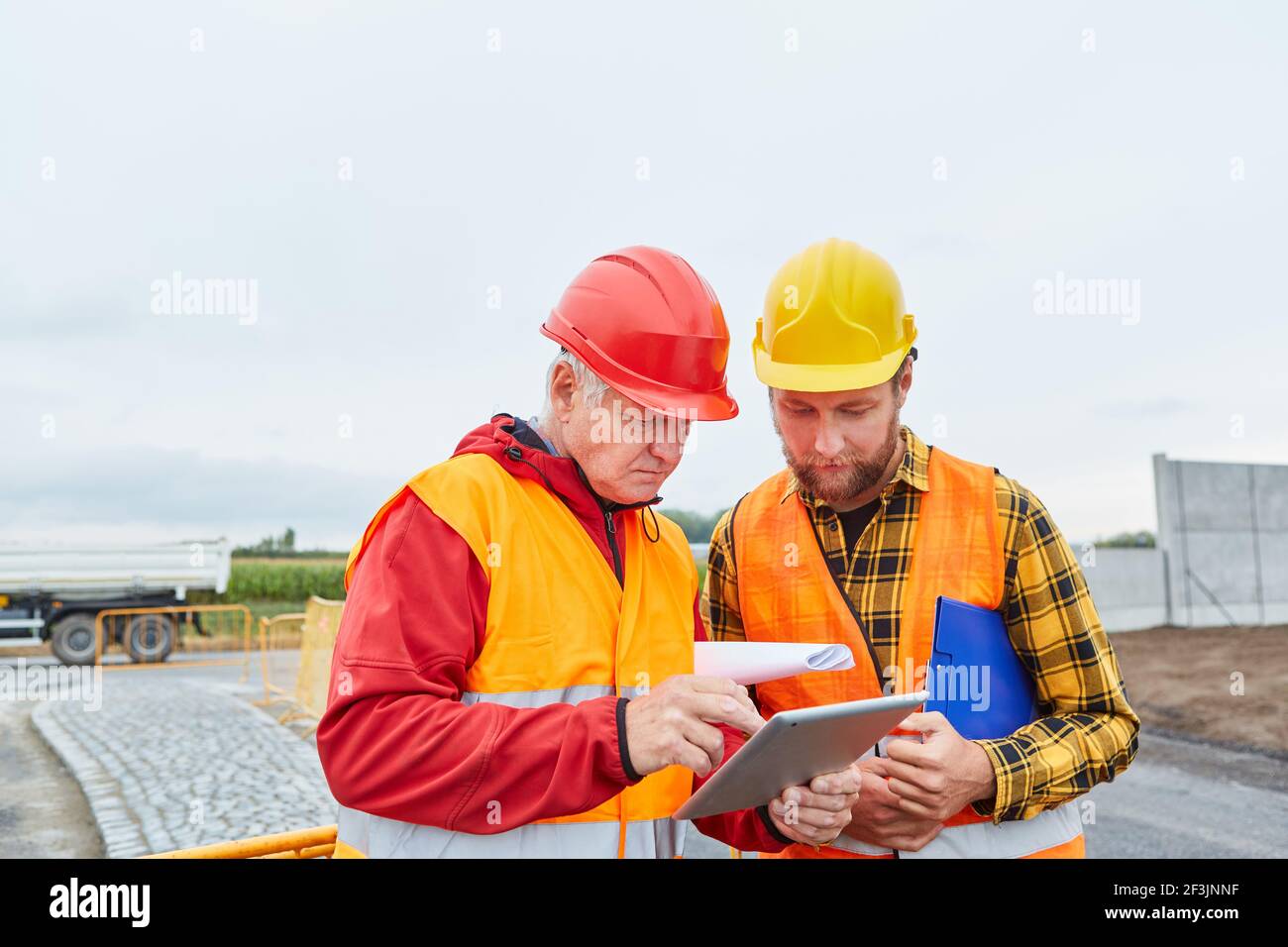 Two construction workers using tablet computer on construction site in road construction or house building Stock Photo