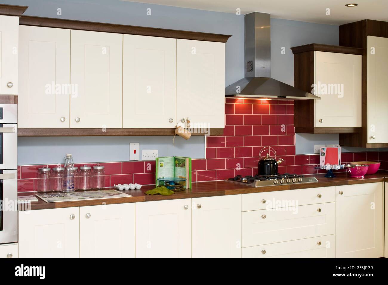 kitchen with red tiled wall and cream presses, hob and extractor fan Photo  by Kevin Mcfeely Stock Photo - Alamy