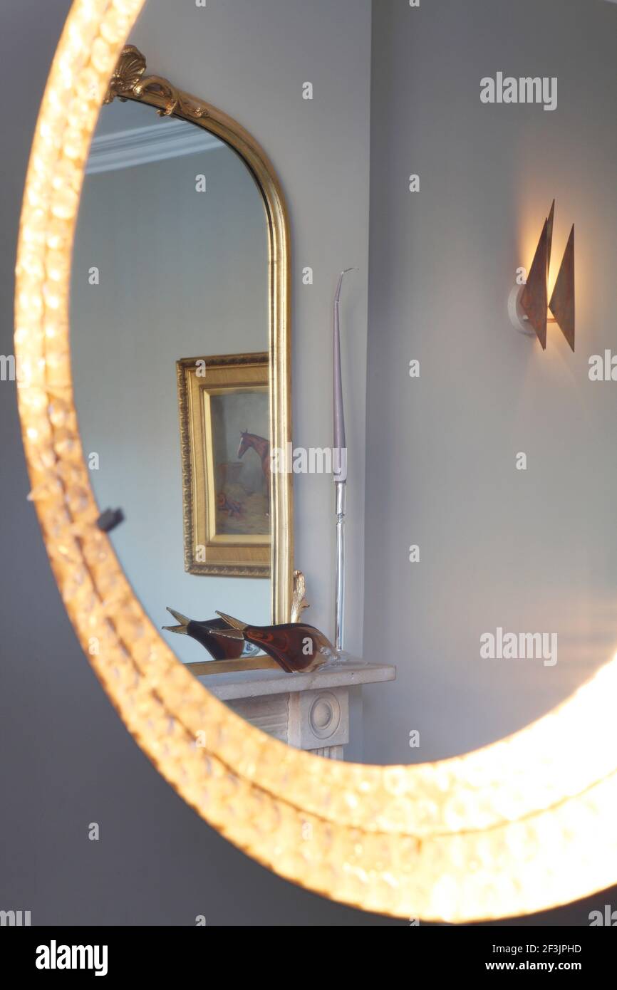 Double reflection with lights on. Gilt framed mirror over fireplace ...
