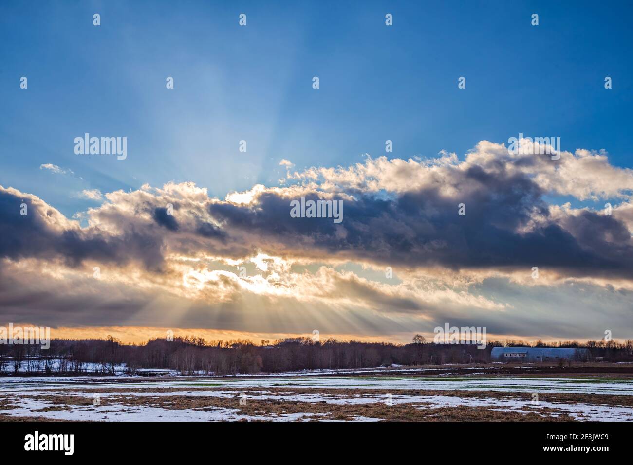 Sunset over the snowy field with sunrays Stock Photo