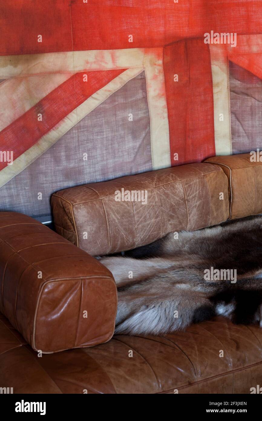 Worn brown leather sofa in front of Union Jack flag, London Stock Photo