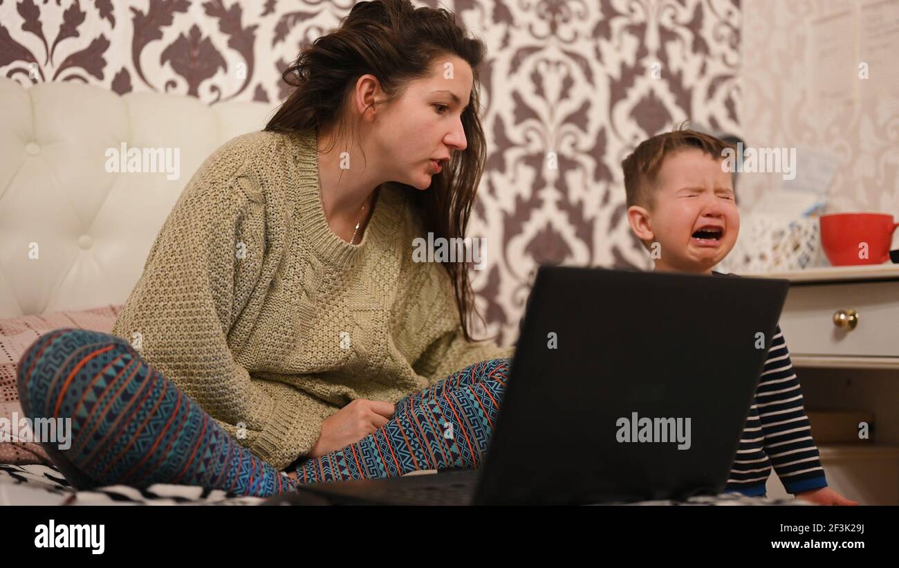 Mother works at the computer, the child is crying . High quality photo ...