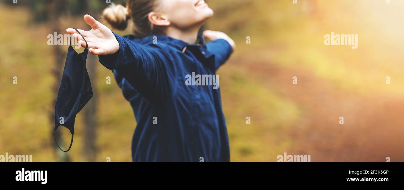 woman enjoying nature and fresh air with removed face mask. mental health and stress relief during pandemic. banner copy space Stock Photo