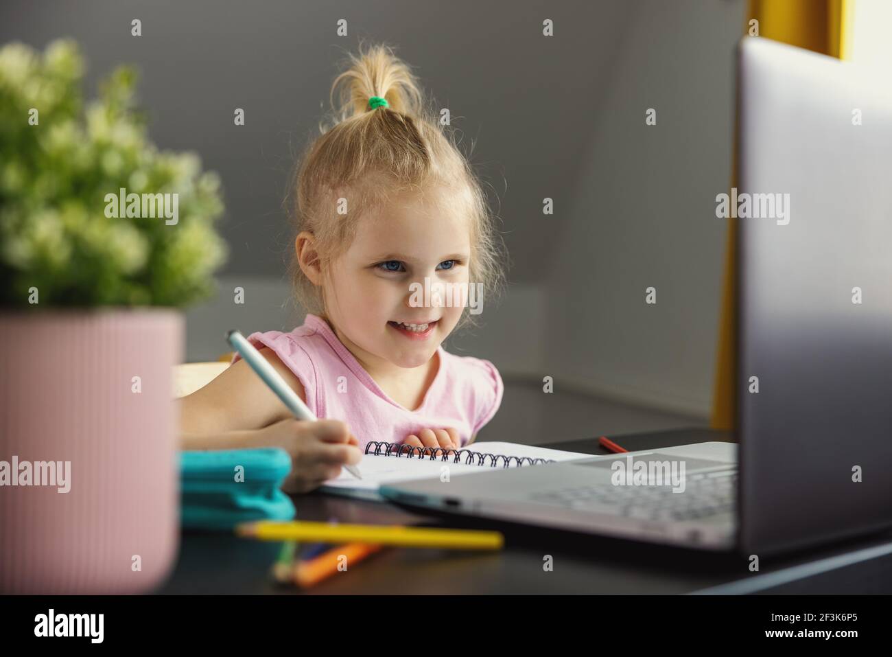 little girl using laptop computer at home for distance learning or homework. e-learning Stock Photo