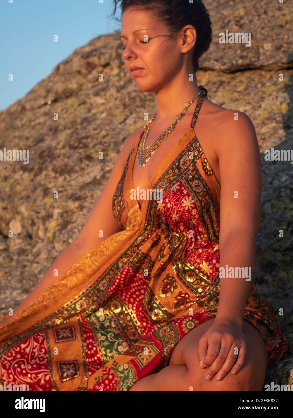 Female with orange silk dress in deep meditating breathing calmly in the  sunset Stock Photo - Alamy