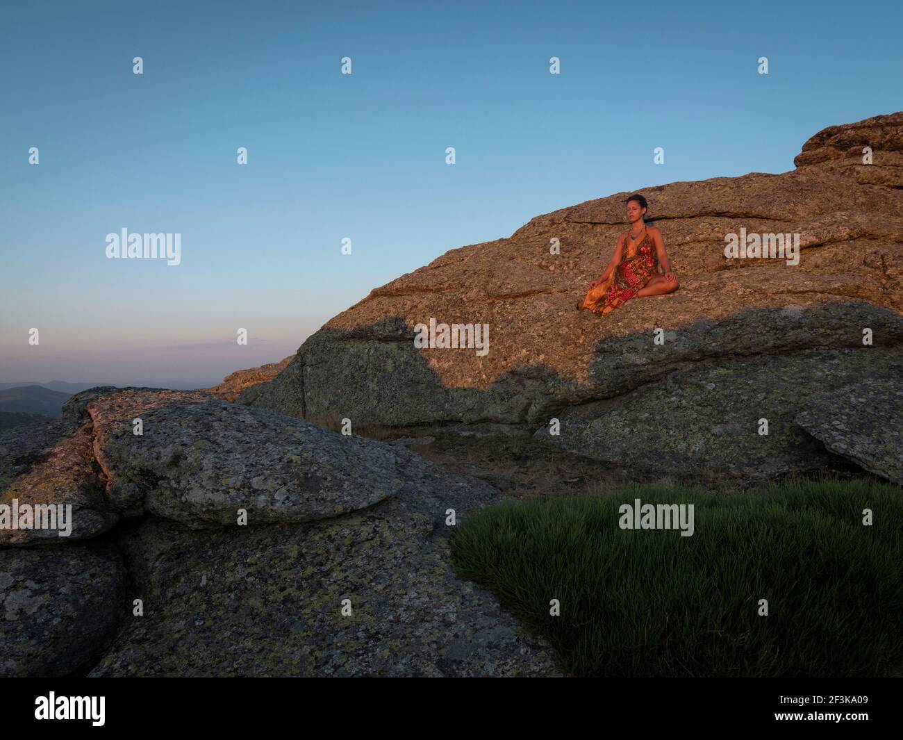Female meditating in the sunset on top of a granite mountain Stock ...
