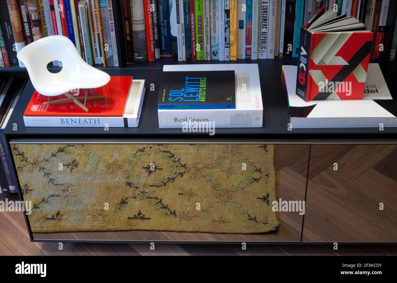 Scale model of Eames La Chaise, Vitra, and a selection of design and art  books on top of a low storage cupboard with reflective front panel by B&B  Ita Stock Photo -
