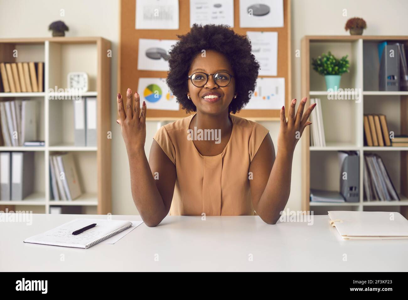 Portrait african american woman sitting at office desk with raised ...