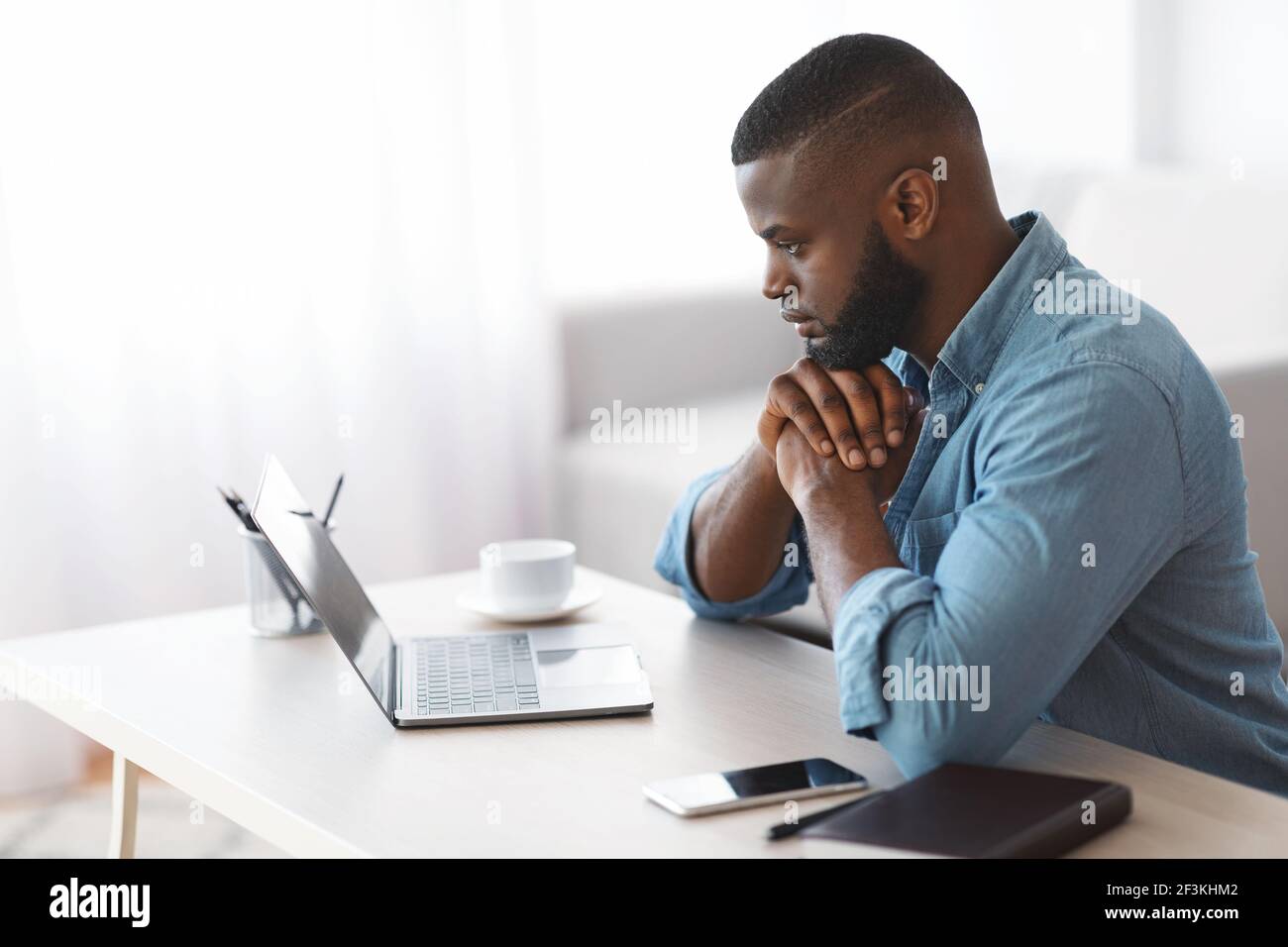 Pensive African American Man Working With Laptop At Home, Side View Stock Photo