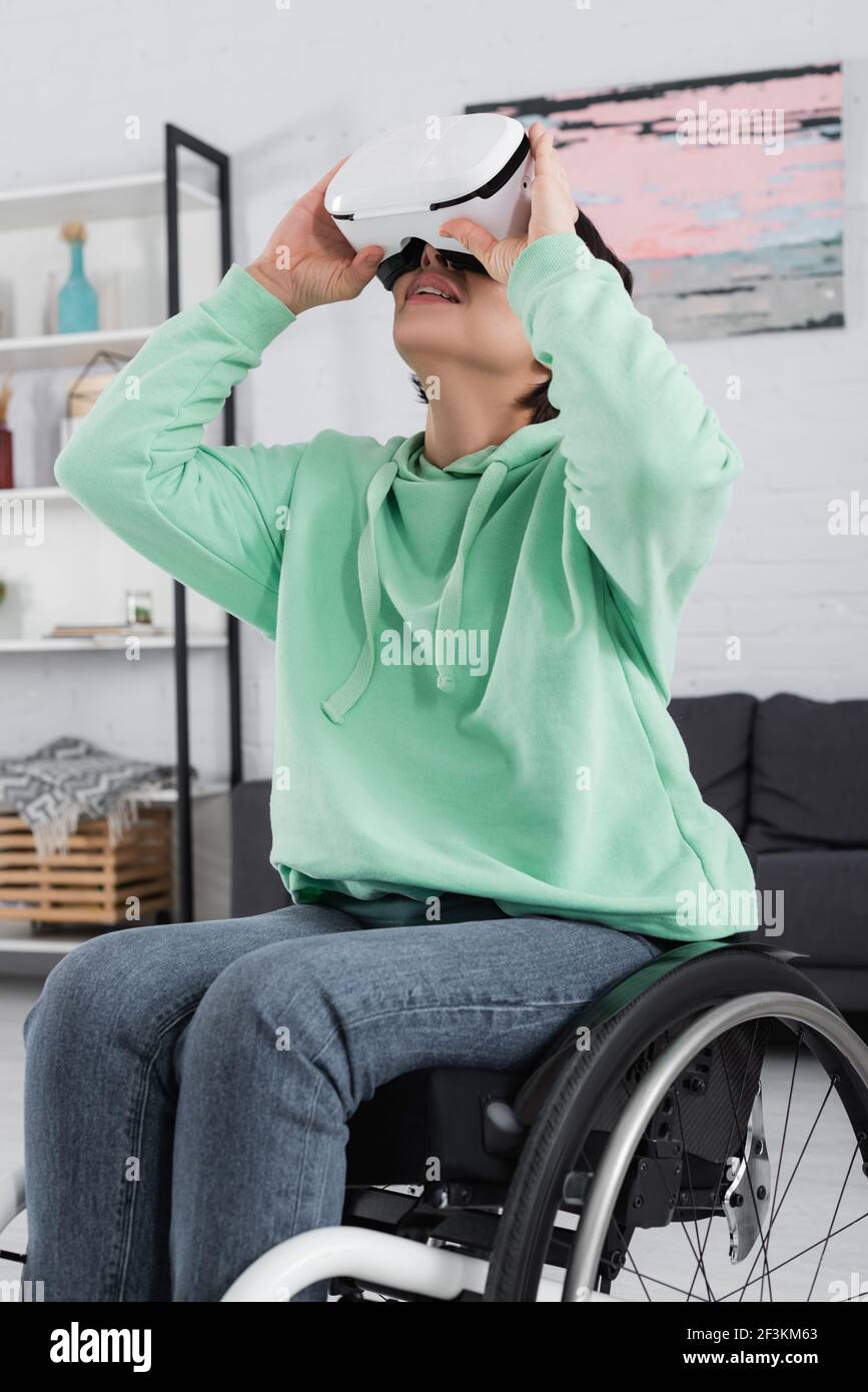 Smiling handicapped woman in vr headset sitting in wheelchair Stock Photo