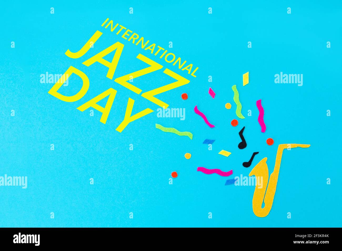 Festival and holiday. A cutted out of felt saxophone on a blue background. Flat lay. International Jazz Day. Stock Photo