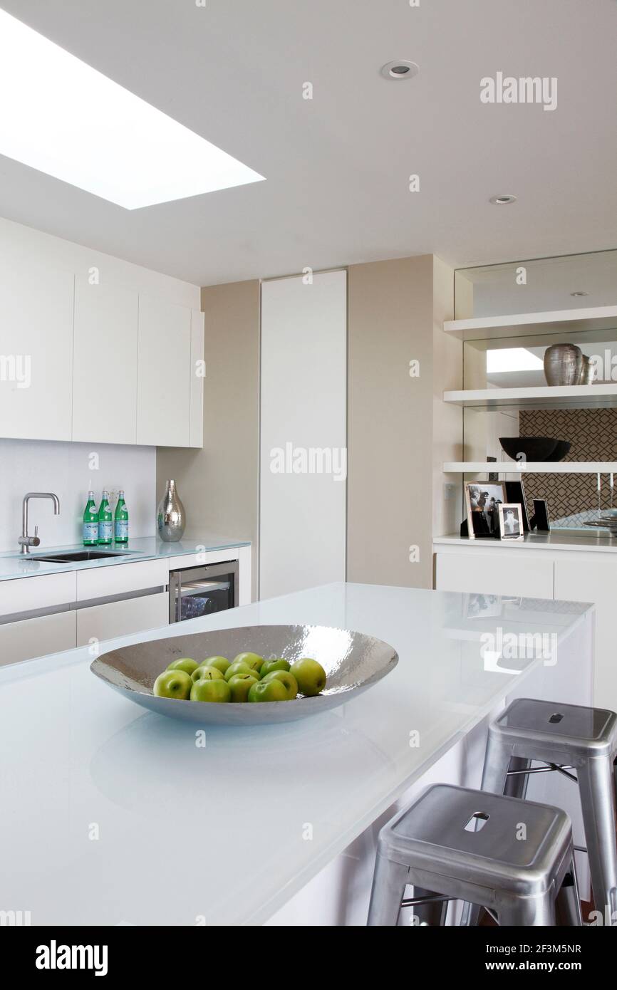 Kitchen with metallic platter of green apples on glass topped island unit in UK show home Stock Photo