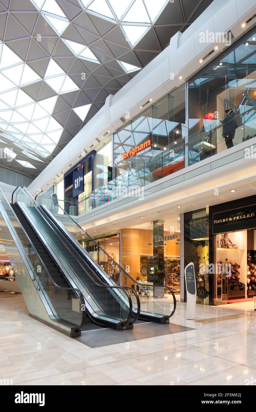 Escalators beneath fluid roof with triangular glazing panels