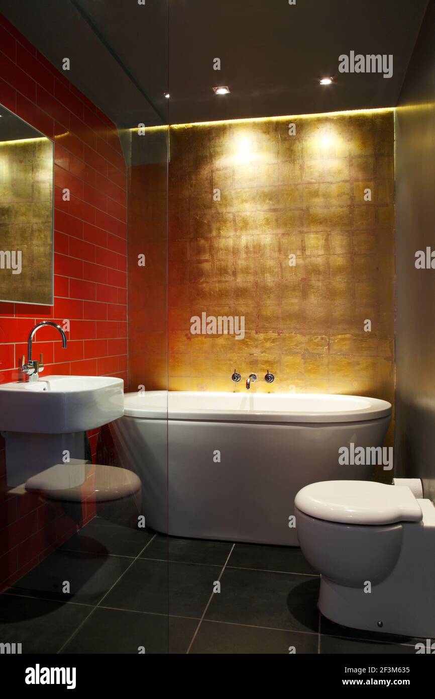 Dramatic bathroom with gold leaf wall behind bath, red wall tiles and black  floor tiles | Architect: Laura Clark | Stock Photo - Alamy, image size:866x1390