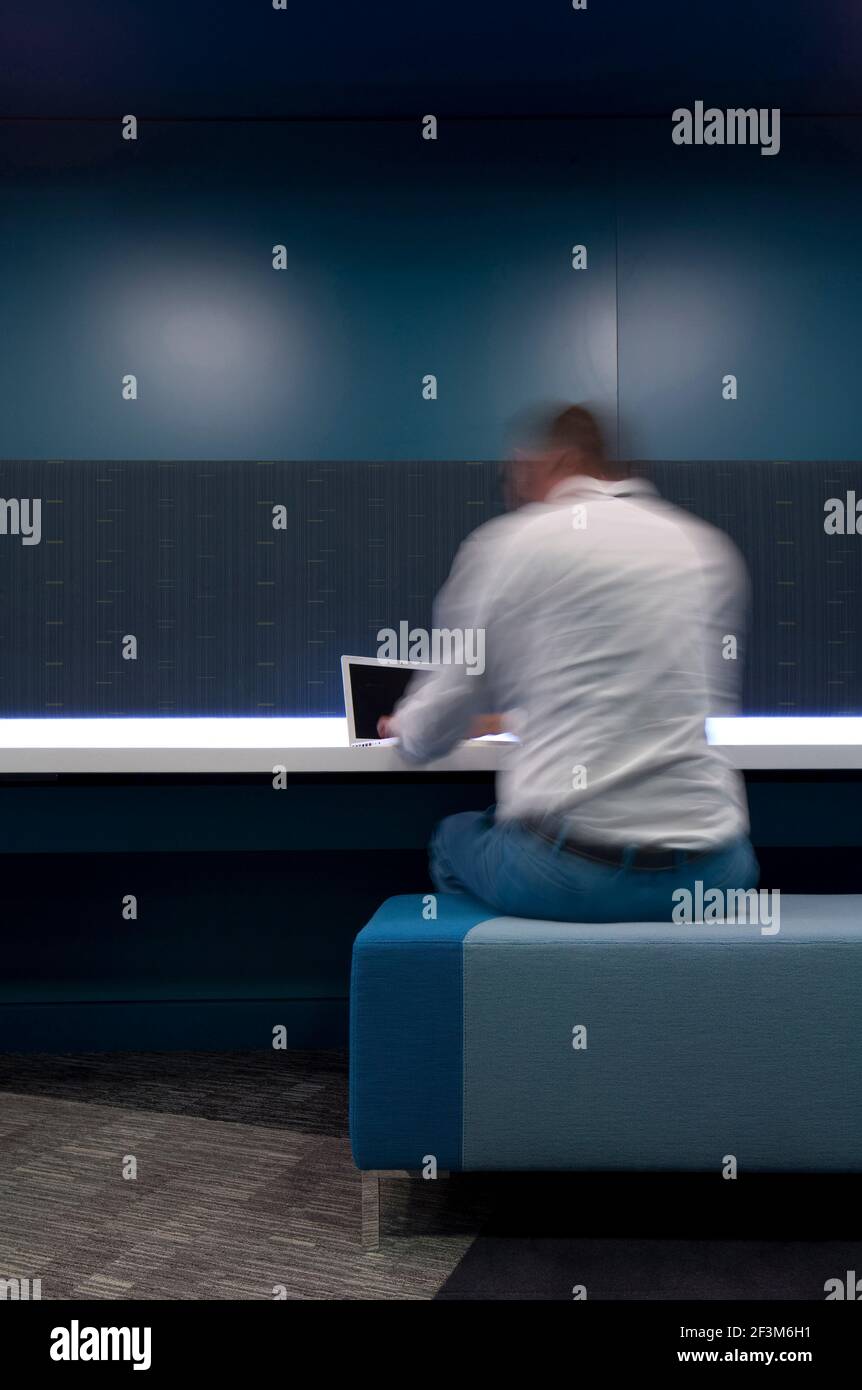 Man sitting working on laptop in interior working space, UK Stock Photo