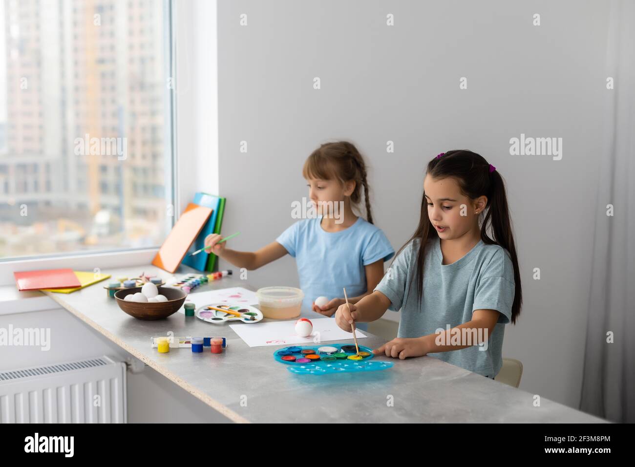 two little girls at the table with paints for drawing Stock Photo - Alamy