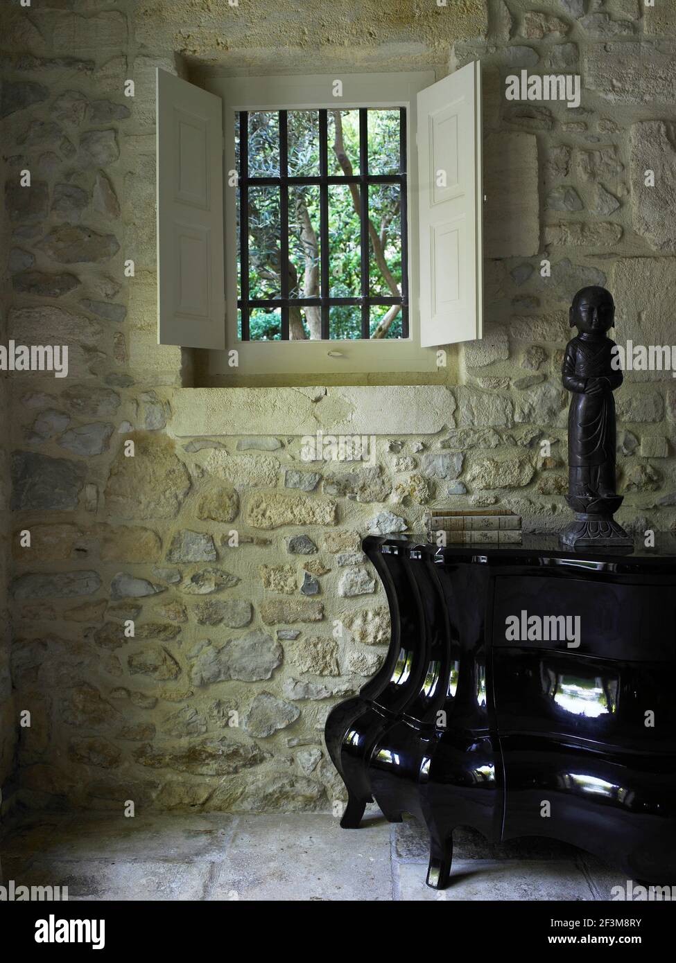 Exposed stonewall with window, Buddhist sculpture on metal table in