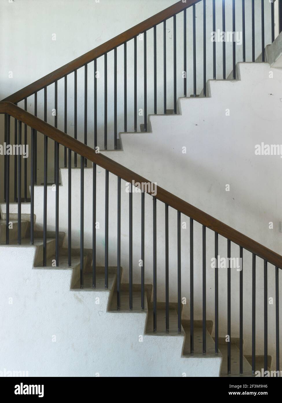 Marble staircase with metal railings and wooden banister in residential