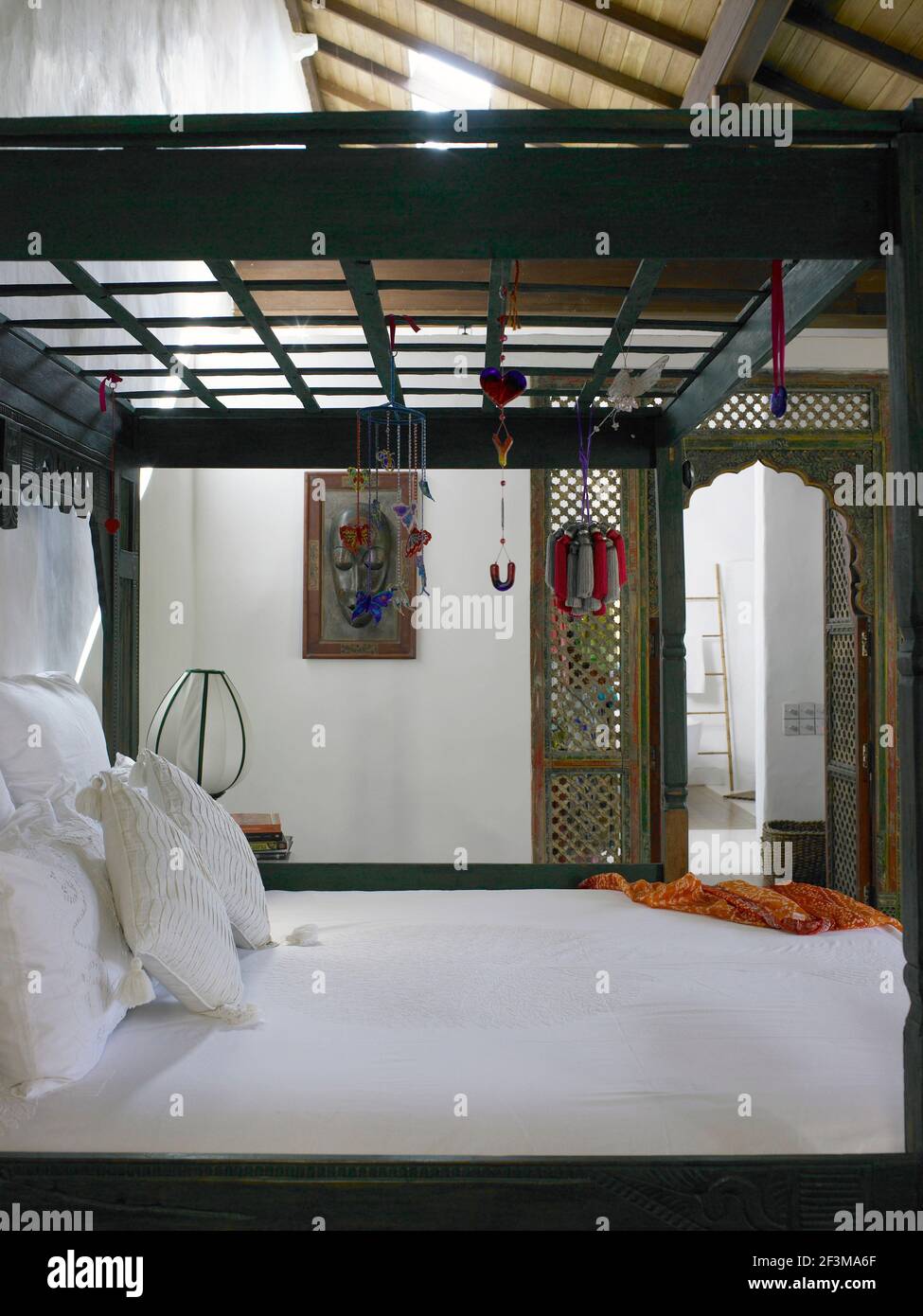 Bedroom with wooden framed four poster bed with hanging mobiles in