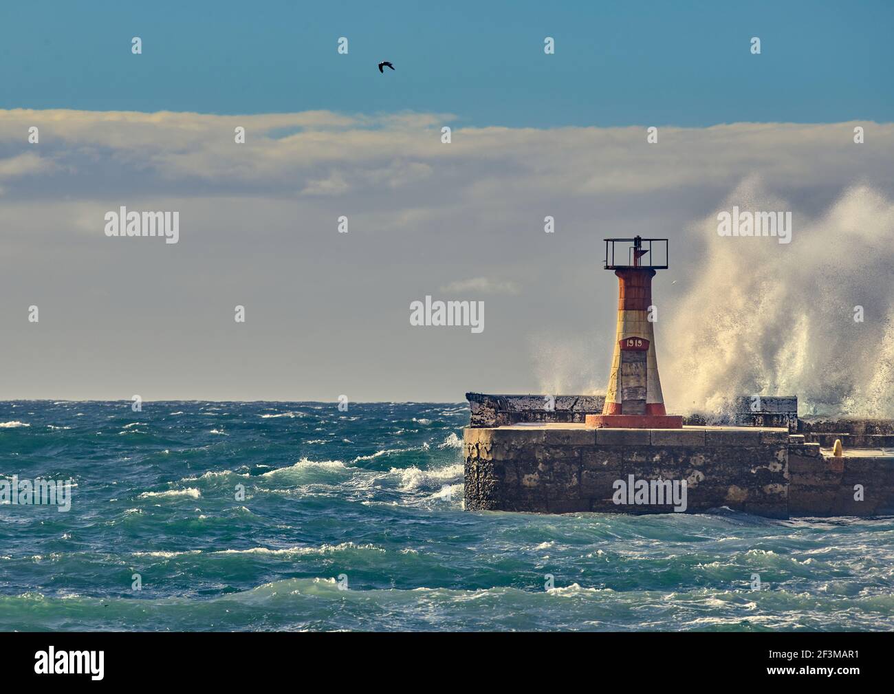 Kalk Bay Harbour Lighthouse with breaking waves Stock Photo