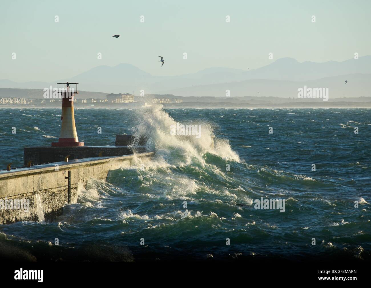 Kalk Bay Harbour Lighthouse with breaking waves Stock Photo