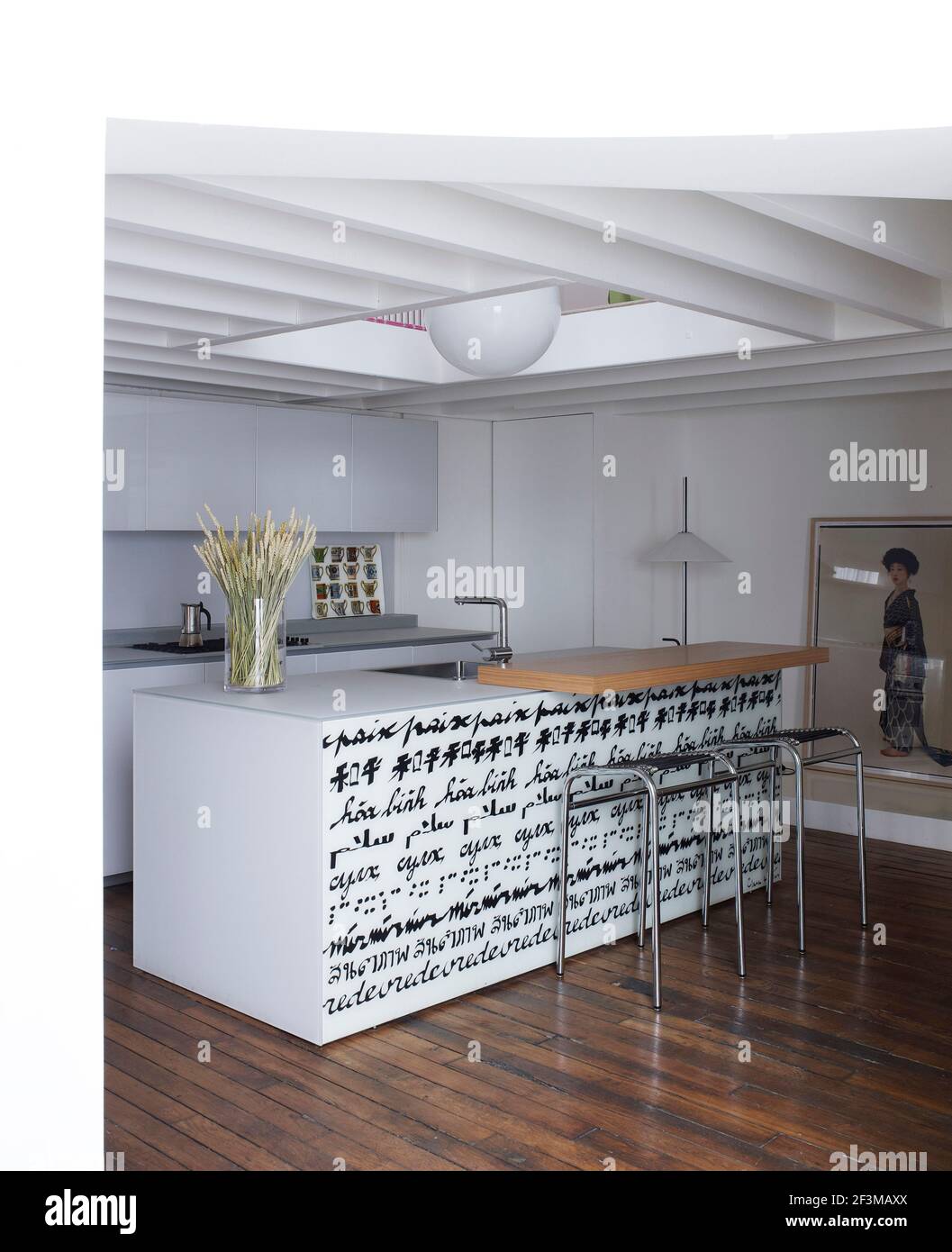 Modern kitchen with oriental painting and island decorated in calligraphic with breakfast bar and stools in French residential home. Stock Photo