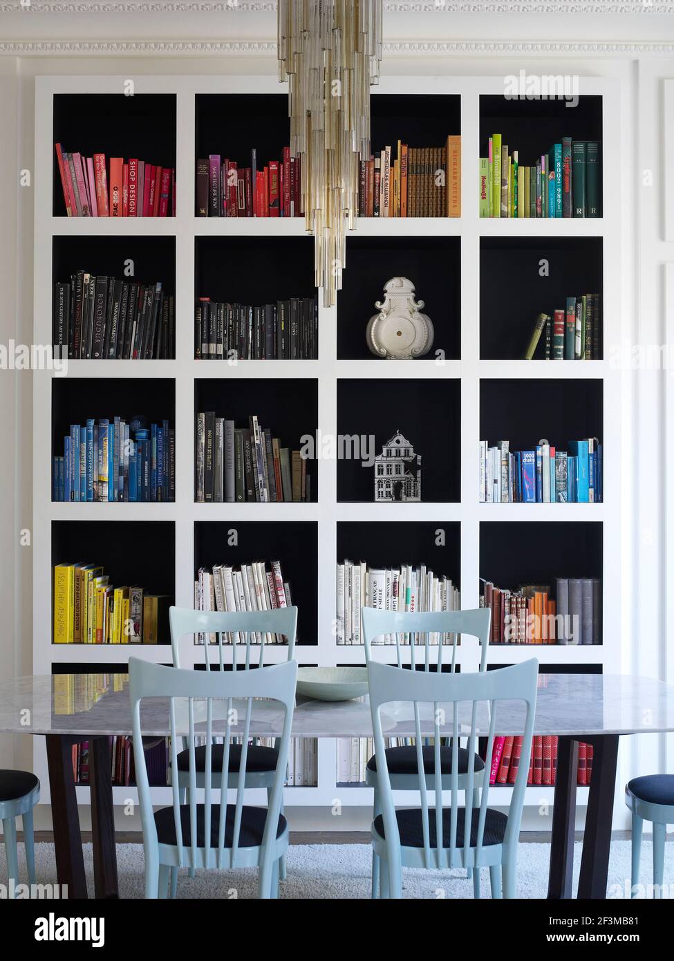 Shelving unit with books and ornaments next to table and hairs with