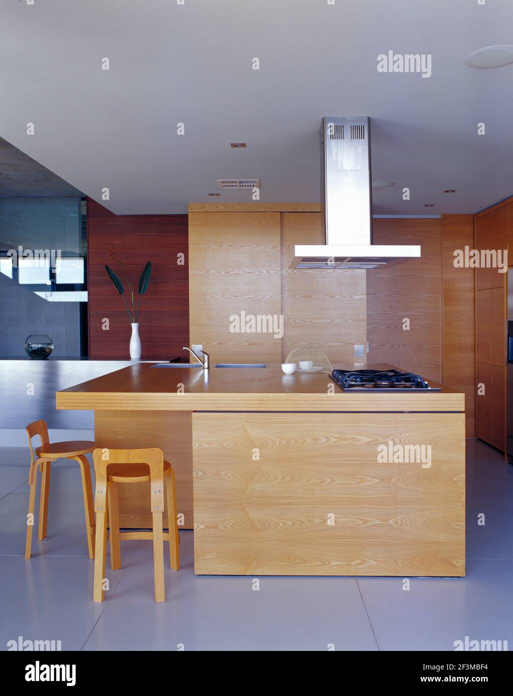 Open plan kitchen with hanging extractor fan, breakfast bar and stools
