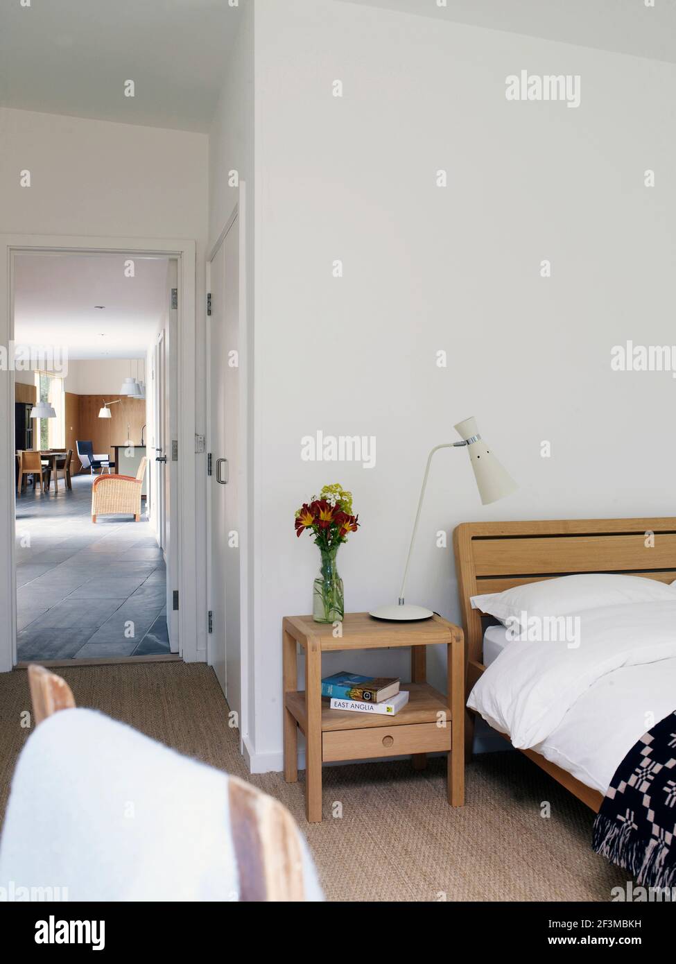 Bedroom area with cut flowers and spot lamp on bedside table next