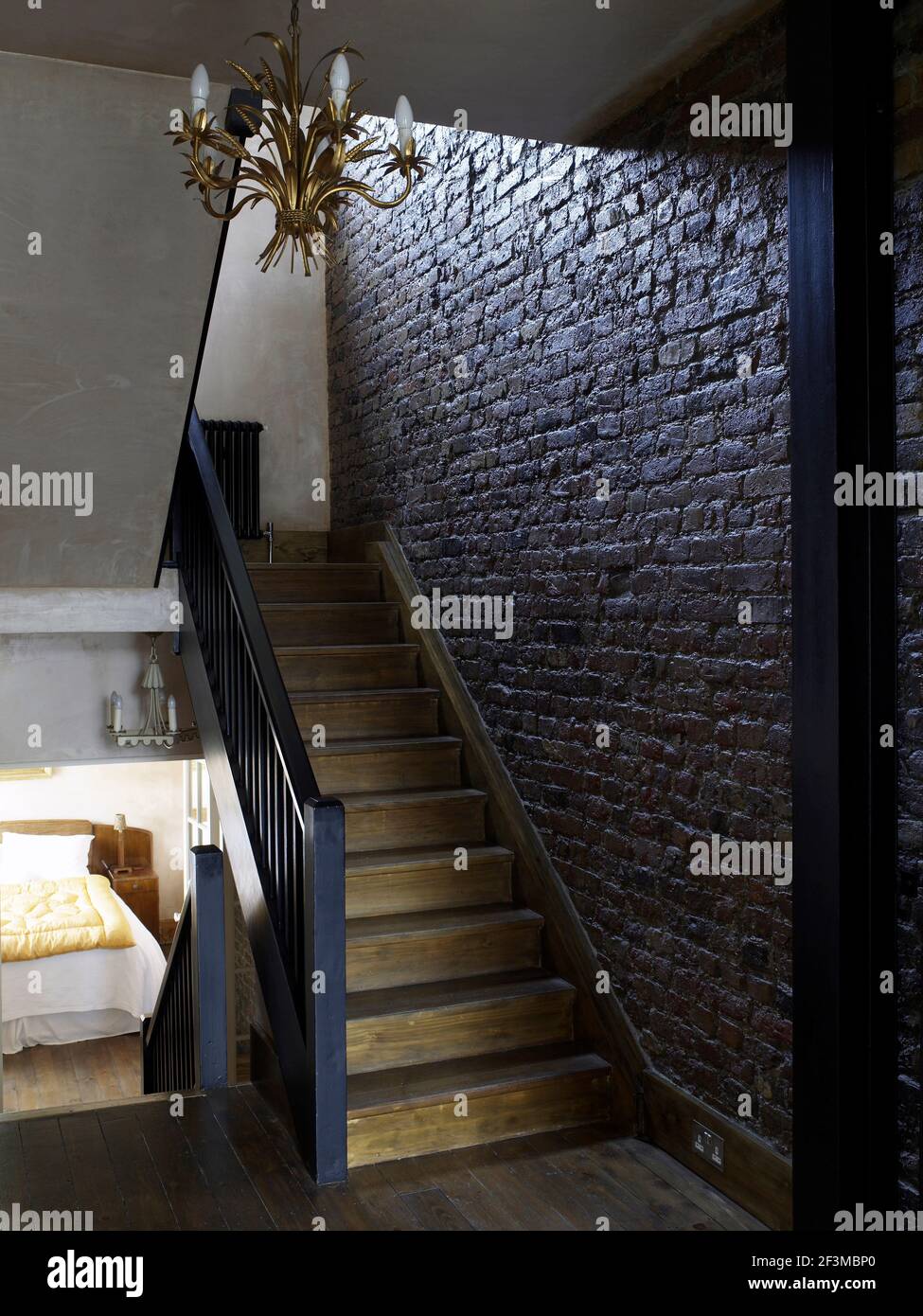 Wooden staircase with exposed brick wall in residential home, UK Stock