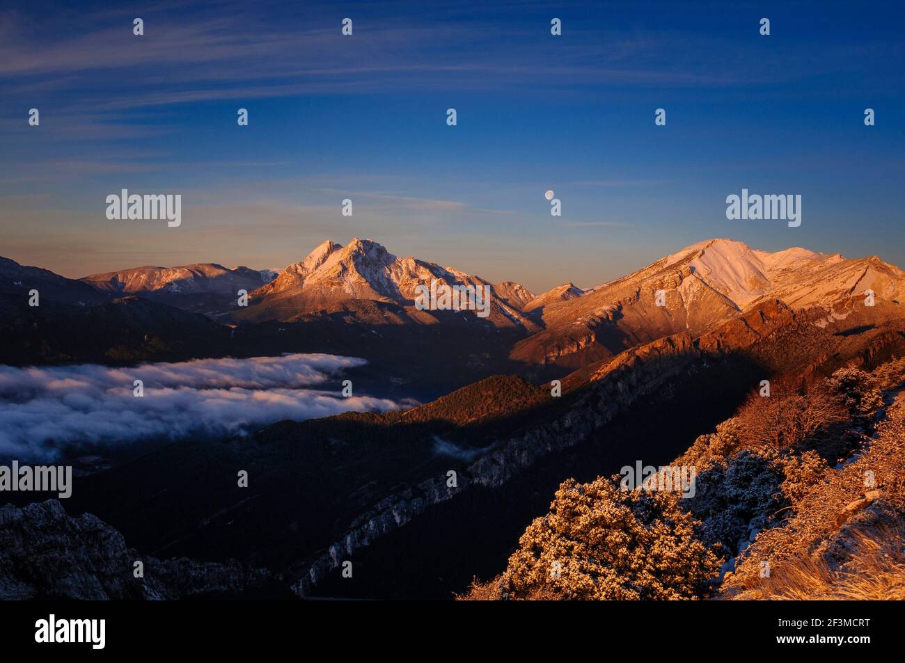 Sunrise at Pedraforca and Alt Berguedà region with Full Moon, viewed from Coll de Pal viewpoint (Berguedà, Catalonia, Spain, Pyrenees) Stock Photo