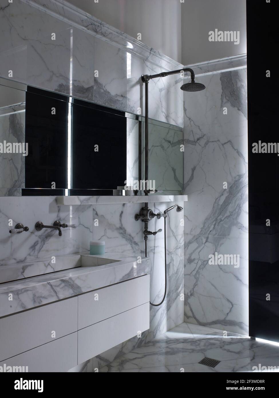 Dappled natural light in marble wet room with large industrial shower head and large basin in residential house, France. Stock Photo