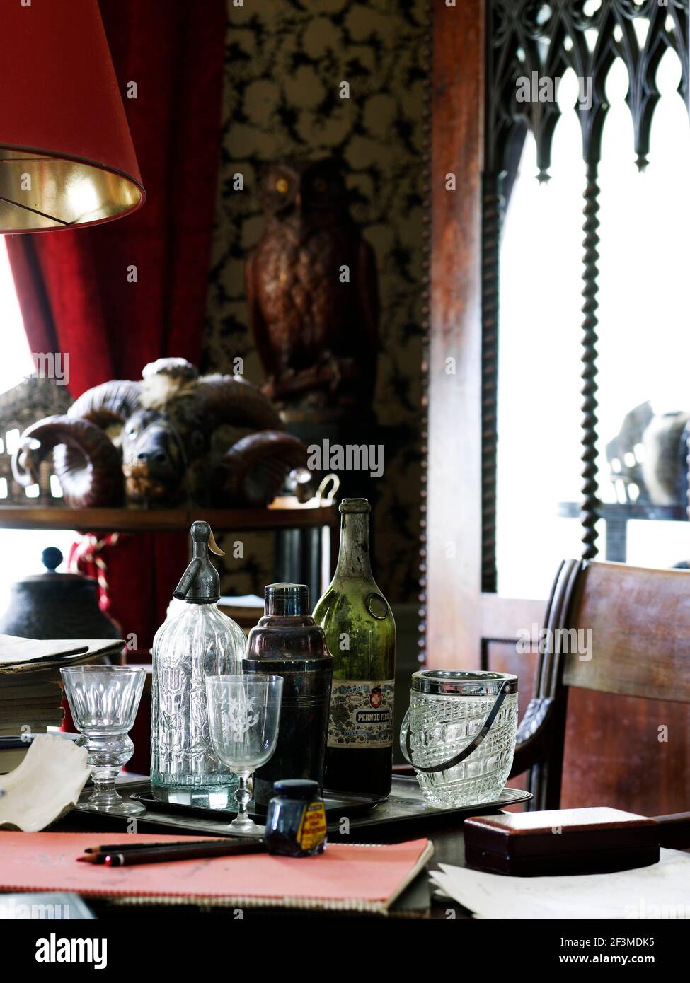 Antique bottles and decanters with paper and in on desk with animal skull in background of residential house, France. Stock Photo
