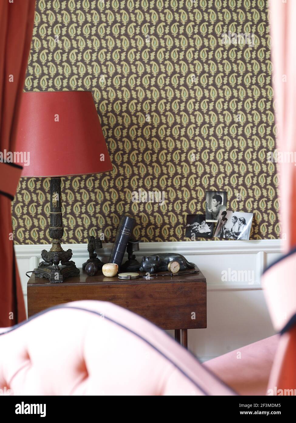 Wall paper detail with black and white photos on dado and table with curiosities and lamp Stock Photo