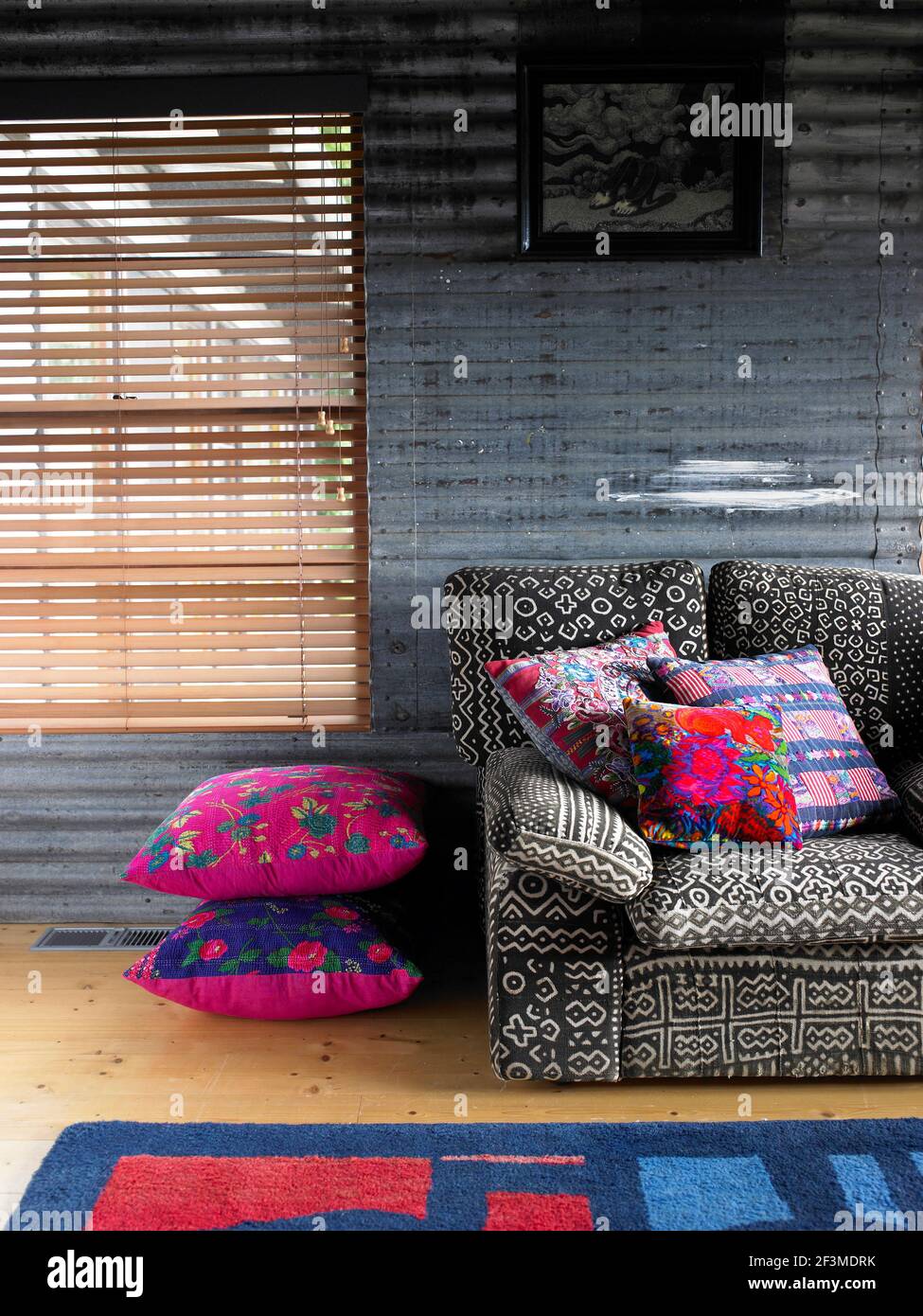 Corrugated wall in living room with soft colourful furnishings and artwork in residential house, Australia. Stock Photo