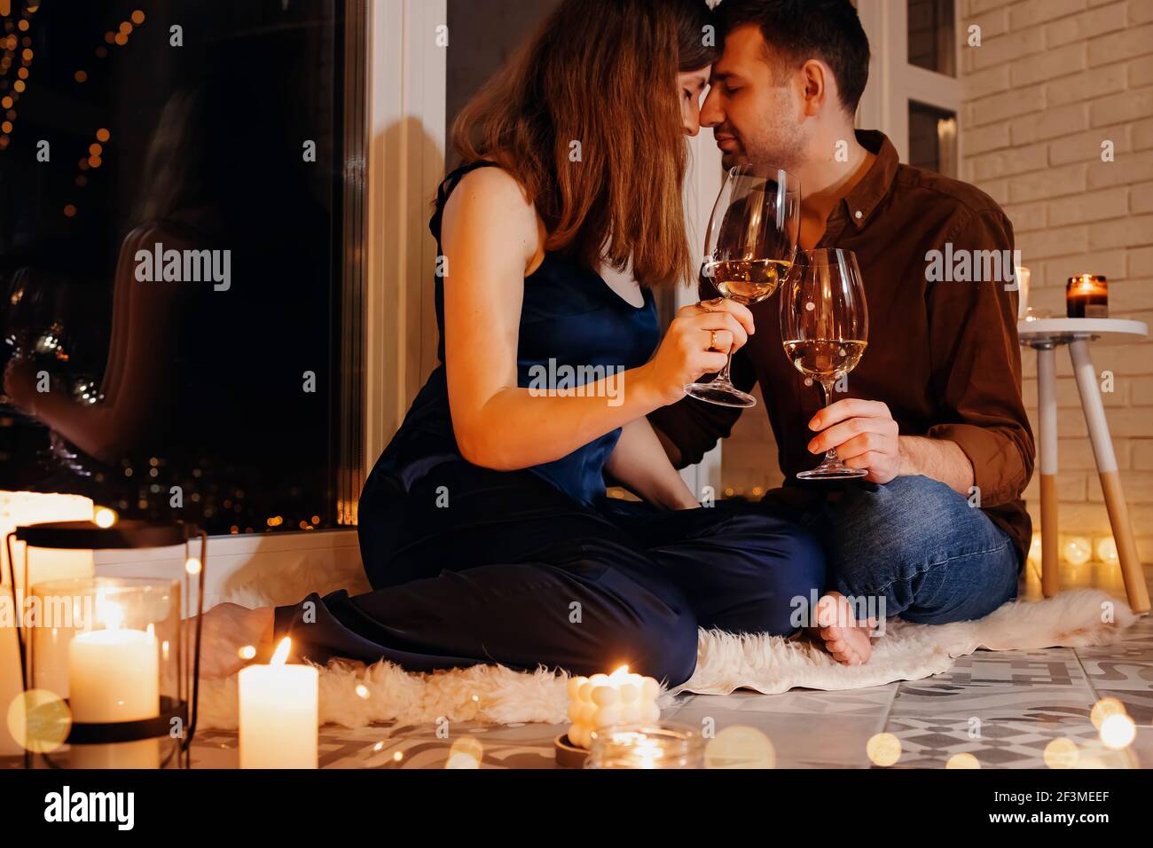 Man and woman having date, sitting on the floor with a lot of burning candles Stock Photo
