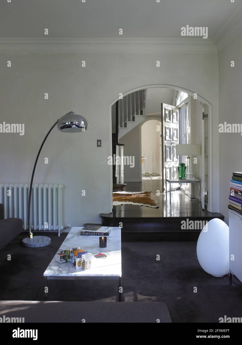 Living room with marble topped coffee table and view through arch into hallway in residential house, Australia Stock Photo