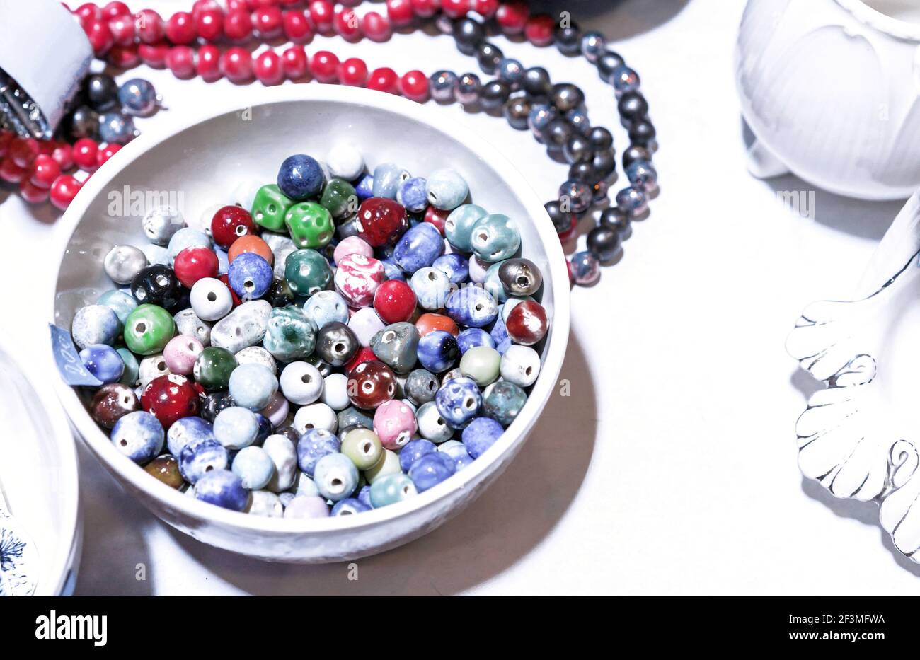 Multicolored beads from natural gems in a white cup. Stock Photo