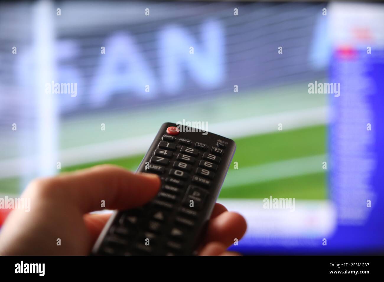 A male hand switching the channels to a soccer match with a remote