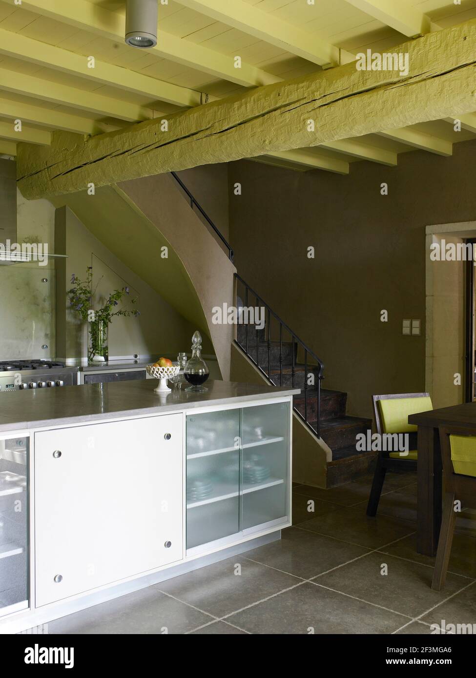 Open plan kitchen and dining room with staircase in barn conversion, France Stock Photo