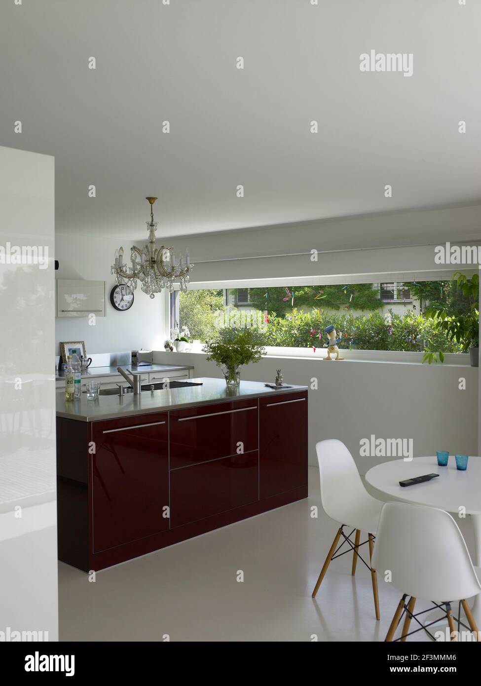 Table and chairs in open plan kitchen with red island unit, Switzerland Stock Photo