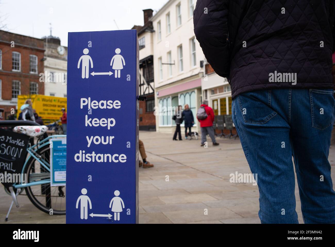 Social distancing keep your distance signs in the market town of Romsey Hampshire England and people meeting for coffee in the town square. Stock Photo