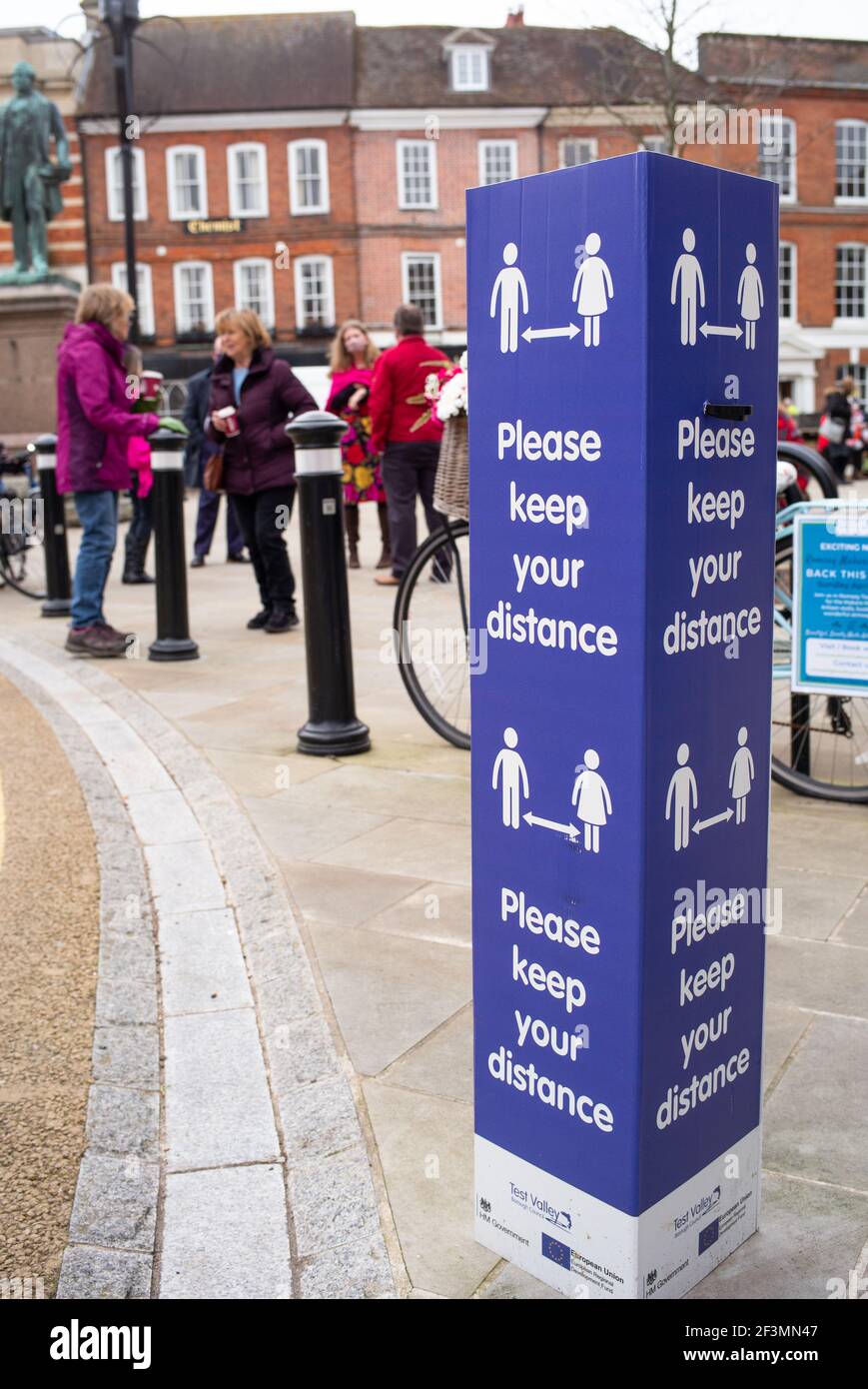 Social distancing keep your distance signs in the market town of Romsey Hampshire England and people meeting for coffee in the town square. Stock Photo