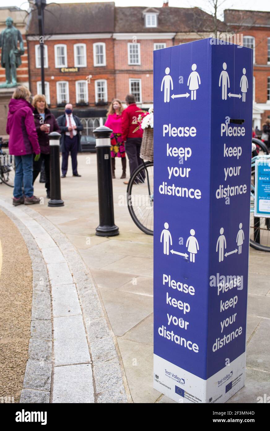 Social distancing keep your distance signs in the market town of Romsey Hampshire England and people meeting for coffee in the town square. Stock Photo