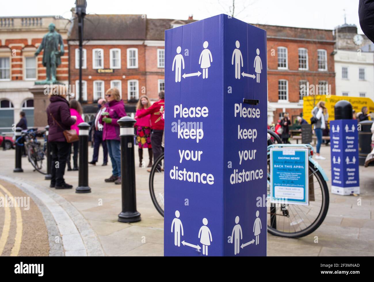 Social distancing keep your distance signs in the market town of Romsey Hampshire England and people meeting for coffee in the town square. Stock Photo