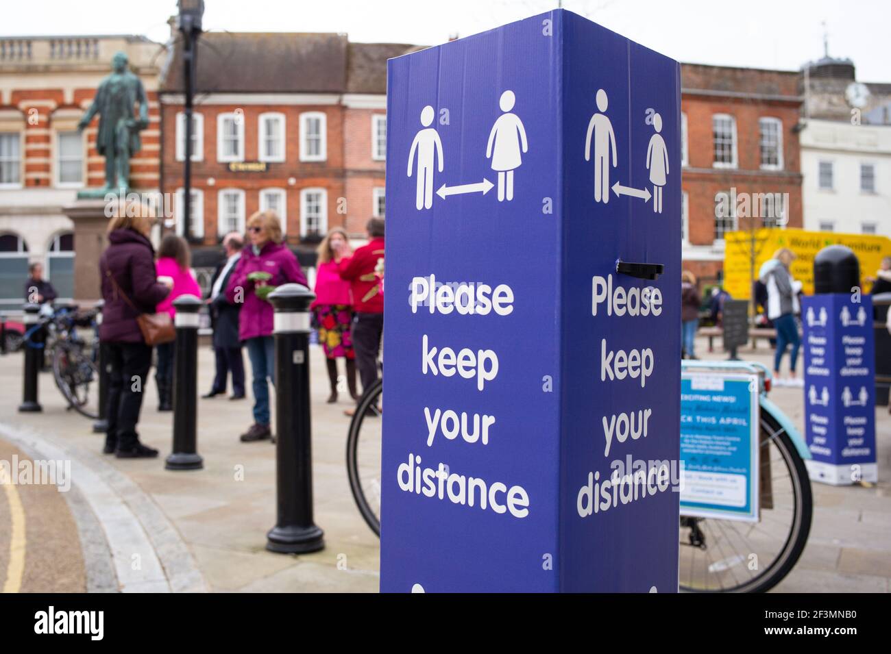 Social distancing keep your distance signs in the market town of Romsey Hampshire England and people meeting for coffee in the town square. Stock Photo